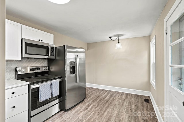 kitchen with white cabinetry, stainless steel appliances, light hardwood / wood-style floors, and tasteful backsplash