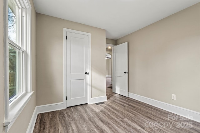 unfurnished bedroom featuring multiple windows and wood-type flooring