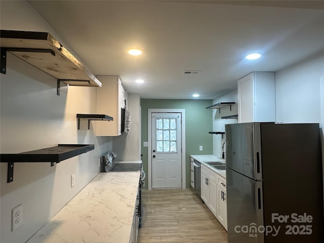 kitchen featuring stainless steel appliances, sink, light hardwood / wood-style flooring, and white cabinets