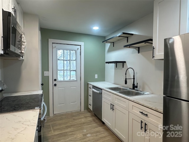 kitchen featuring sink, white cabinetry, light hardwood / wood-style flooring, appliances with stainless steel finishes, and light stone countertops