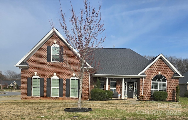 traditional home featuring a front yard and brick siding