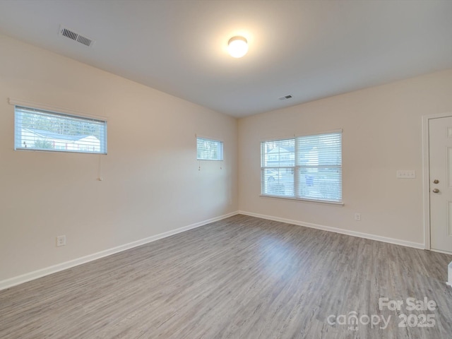 empty room with a wealth of natural light and light hardwood / wood-style floors