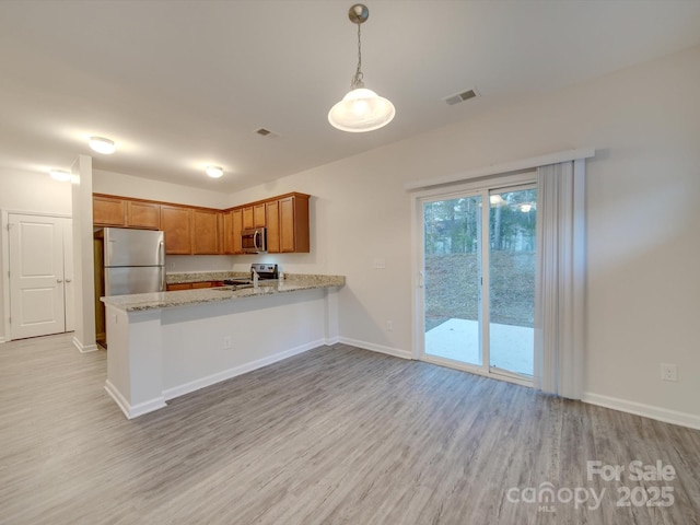 kitchen featuring light hardwood / wood-style flooring, appliances with stainless steel finishes, light stone counters, decorative light fixtures, and kitchen peninsula