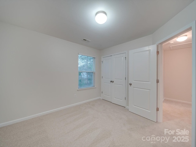 unfurnished bedroom featuring light colored carpet and a closet