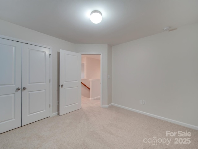 unfurnished bedroom featuring light colored carpet and a closet