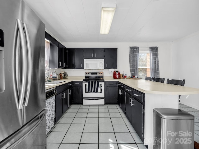 kitchen featuring light tile patterned flooring, appliances with stainless steel finishes, sink, a breakfast bar area, and kitchen peninsula