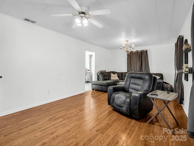 living room with ceiling fan with notable chandelier and light hardwood / wood-style flooring