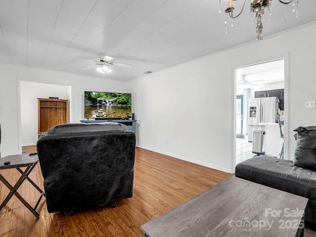 living room with hardwood / wood-style flooring and ceiling fan with notable chandelier