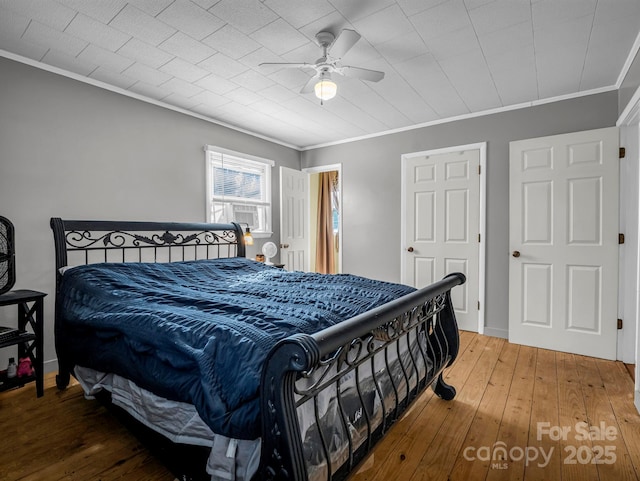 bedroom with hardwood / wood-style flooring, ceiling fan, and crown molding