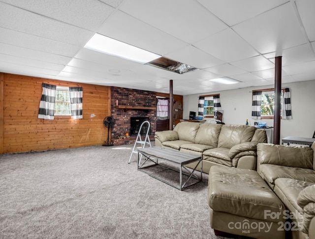 living room with a brick fireplace, carpet floors, a healthy amount of sunlight, and wood walls