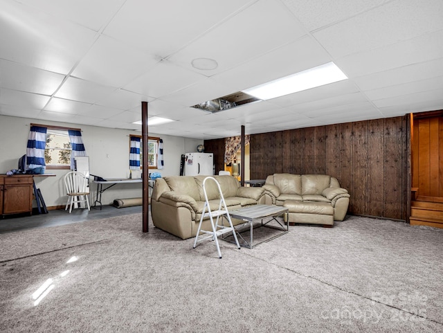 living room with a drop ceiling and wooden walls