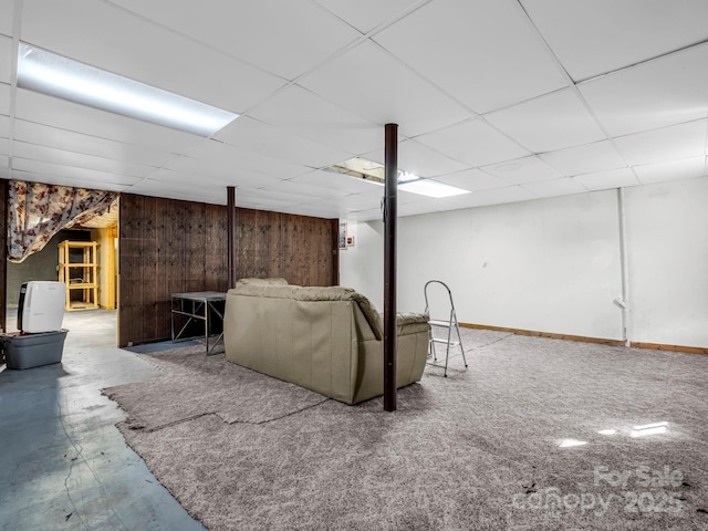 living room with a drop ceiling and wooden walls