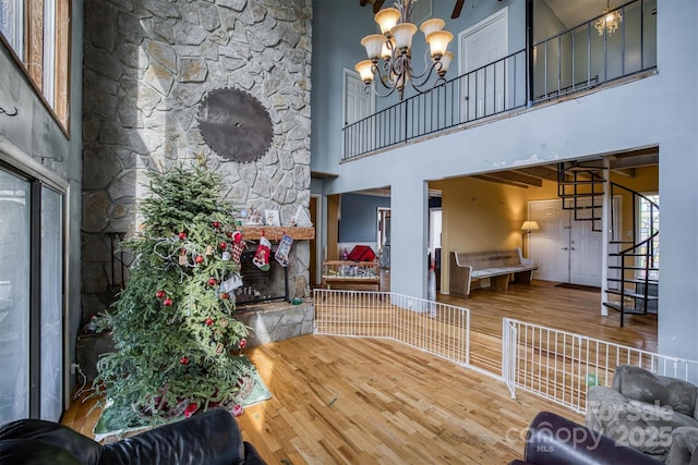 living room with hardwood / wood-style floors, an inviting chandelier, a high ceiling, and a fireplace