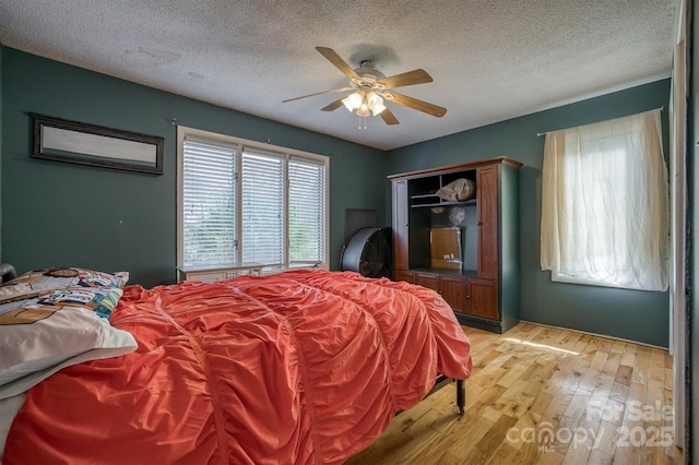 bedroom with light hardwood / wood-style flooring, ceiling fan, and a textured ceiling