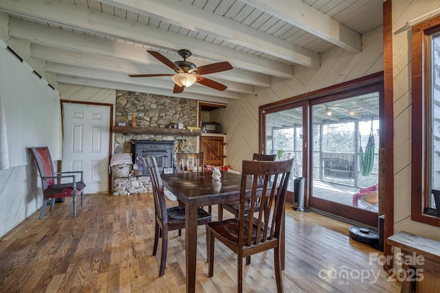 dining area with hardwood / wood-style flooring, wooden walls, and beam ceiling