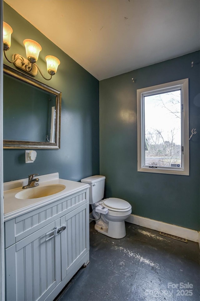 bathroom featuring toilet, vanity, and concrete flooring