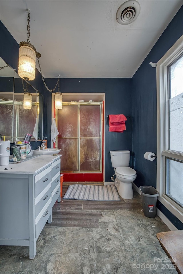 bathroom with toilet, a shower with door, and vanity