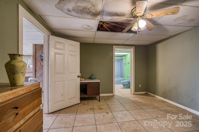 unfurnished bedroom with light tile patterned floors, connected bathroom, and a paneled ceiling