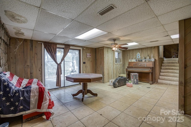 interior space featuring a paneled ceiling and wood walls