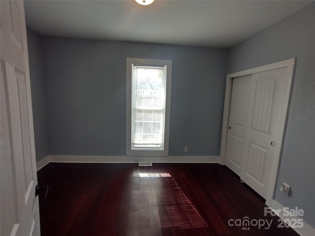 unfurnished bedroom with dark hardwood / wood-style flooring and a closet