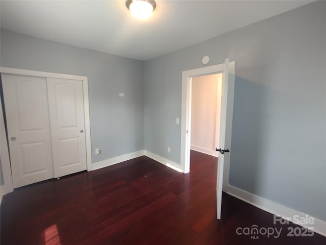 unfurnished bedroom with dark wood-type flooring and a closet