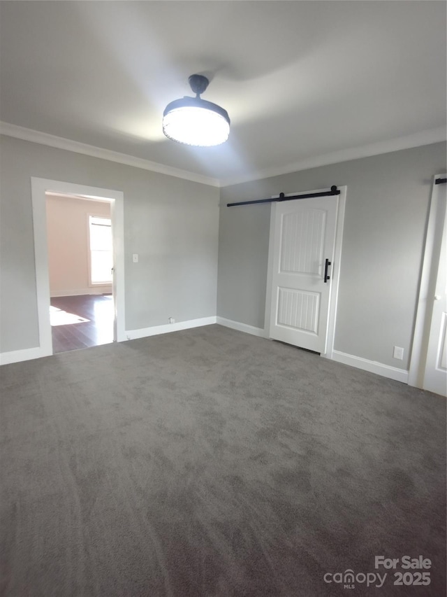 carpeted spare room with ornamental molding and a barn door