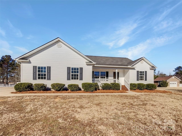 ranch-style home featuring a garage, covered porch, and a front lawn