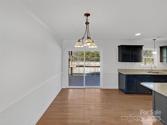 kitchen featuring hanging light fixtures, sink, an inviting chandelier, and light hardwood / wood-style flooring