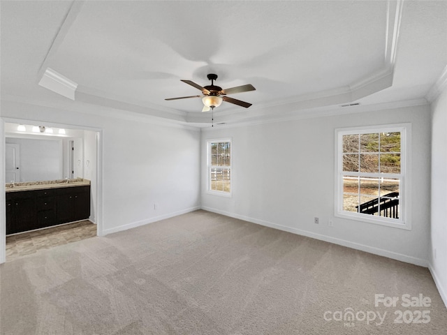 unfurnished bedroom featuring multiple windows, a raised ceiling, and ceiling fan