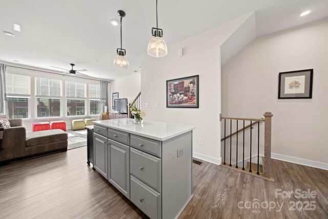 kitchen with gray cabinetry, decorative light fixtures, dark hardwood / wood-style flooring, and a kitchen island