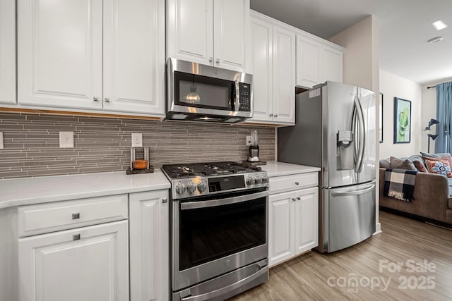 kitchen featuring backsplash, appliances with stainless steel finishes, light wood-type flooring, and white cabinets