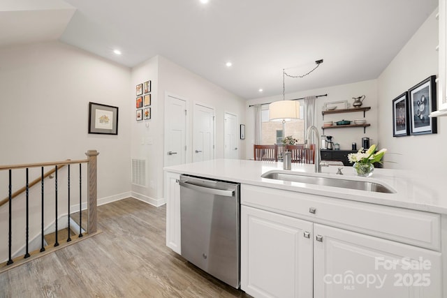 kitchen featuring sink, dishwasher, white cabinetry, decorative light fixtures, and light wood-type flooring