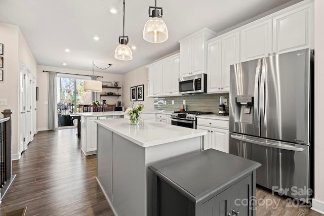 kitchen featuring white cabinetry, stainless steel appliances, a center island, and kitchen peninsula