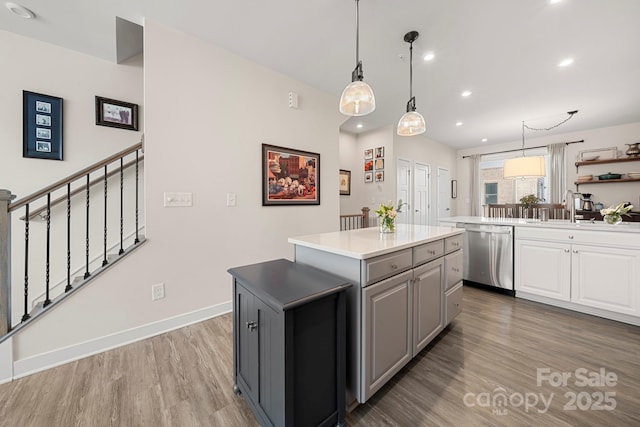 kitchen with pendant lighting, gray cabinets, dishwasher, hardwood / wood-style floors, and a kitchen island