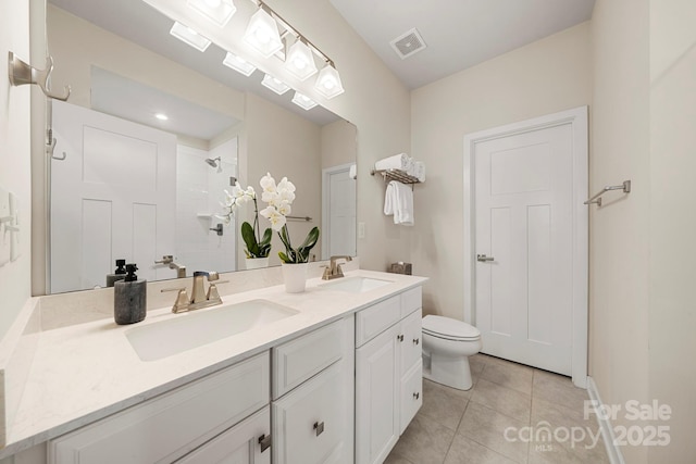 bathroom with toilet, a skylight, a tile shower, vanity, and tile patterned flooring