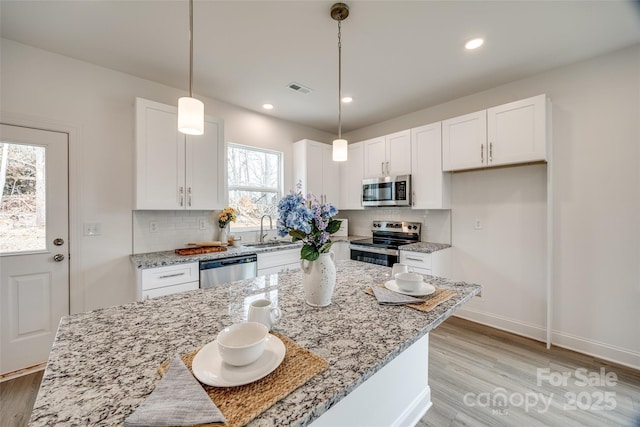 kitchen featuring appliances with stainless steel finishes, pendant lighting, and white cabinets