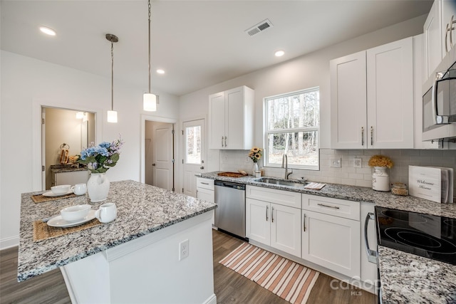 kitchen with dark wood-type flooring, sink, white cabinetry, a center island, and appliances with stainless steel finishes