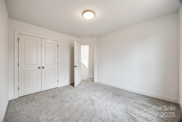 unfurnished bedroom featuring light colored carpet and a closet