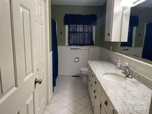 bathroom with vanity, tile walls, tile patterned floors, and toilet