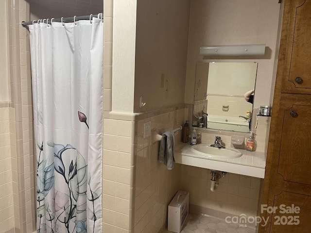 bathroom with walk in shower, tile patterned flooring, sink, and tile walls