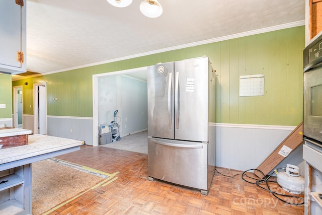 kitchen with a wainscoted wall, crown molding, and freestanding refrigerator