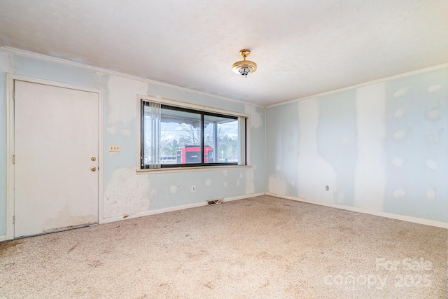 carpeted empty room featuring visible vents, crown molding, and baseboards