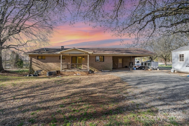 exterior space with brick siding, an attached carport, and driveway