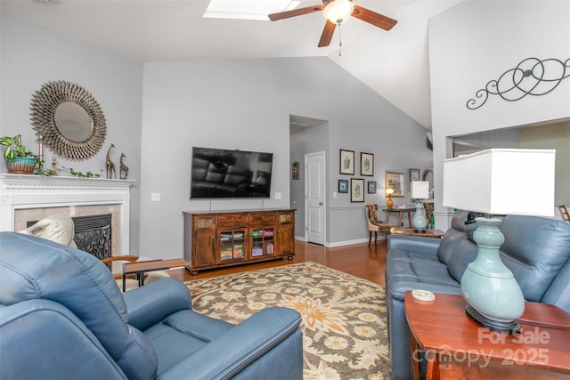 living room with high vaulted ceiling, a skylight, ceiling fan, a high end fireplace, and dark wood-type flooring