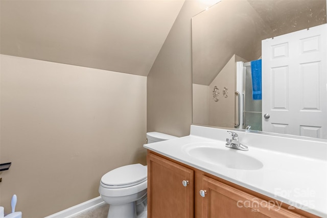 bathroom with a shower with door, vanity, vaulted ceiling, and toilet