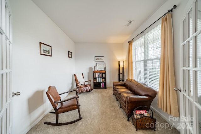 living area featuring french doors and light carpet