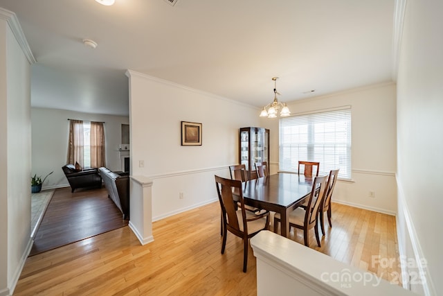 dining area with an inviting chandelier, ornamental molding, and light hardwood / wood-style floors