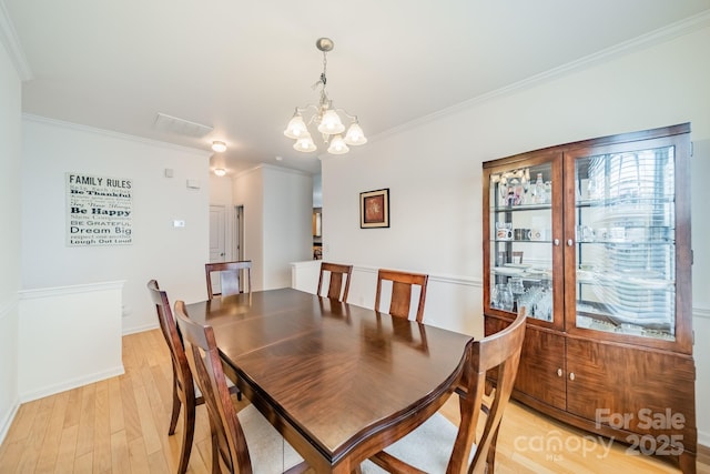 dining space featuring crown molding, a healthy amount of sunlight, a chandelier, and light hardwood / wood-style floors