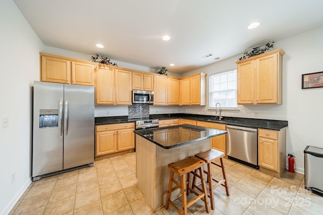 kitchen featuring appliances with stainless steel finishes, light brown cabinetry, sink, and a kitchen island