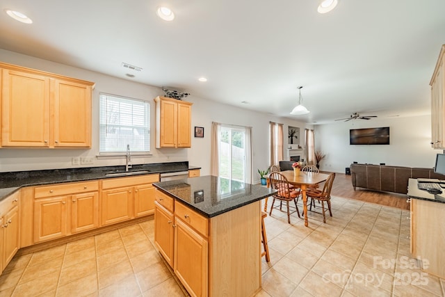 kitchen featuring a kitchen island, pendant lighting, sink, a breakfast bar area, and light brown cabinets